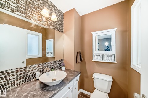 Bathroom featuring a vessel sink set in a countertop with white cabinetry, a large mirror, and a mosaic tile backsplash - 9813 152 Street, Edmonton, AB - Indoor Photo Showing Bathroom