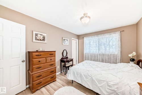 This room features light-colored flooring, neutral-toned walls, and a window with sheer curtains - 9813 152 Street, Edmonton, AB - Indoor Photo Showing Bedroom