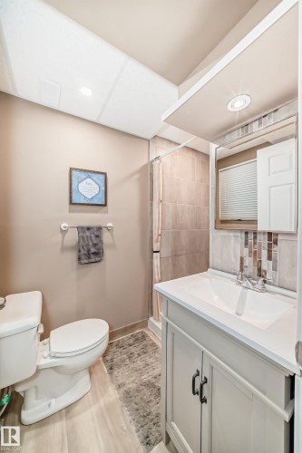The bathroom features a white vanity with a rectangular sink, a shower with tiled walls, and light-colored flooring - 9813 152 Street, Edmonton, AB - Indoor Photo Showing Bathroom