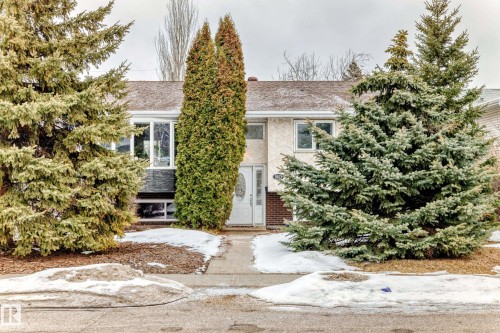 The property features a front facade with white-framed windows and a white front door, set back from a paved walkway - 9813 152 Street, Edmonton, AB - Outdoor