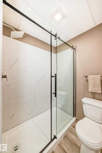 Bathroom featuring a shower with glass enclosure, white tiled walls, and a rainfall showerhead - 9813 152 Street, Edmonton, AB - Indoor Photo Showing Bathroom