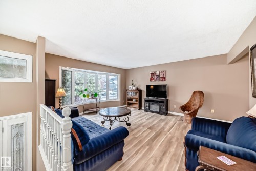 The living area features light-toned flooring, a bay window, and a white staircase railing - 9813 152 Street, Edmonton, AB - Indoor Photo Showing Living Room