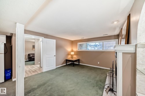 This room features a neutral color palette, a window providing natural light, and green carpeting - 9813 152 Street, Edmonton, AB - Indoor Photo Showing Other Room