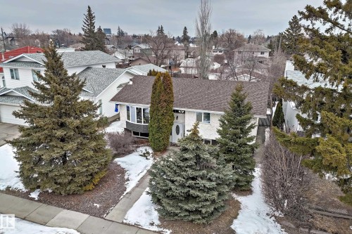 The property features a well-maintained exterior with a brown shingled roof, white siding, and a prominent bay window - 9813 152 Street, Edmonton, AB - Outdoor
