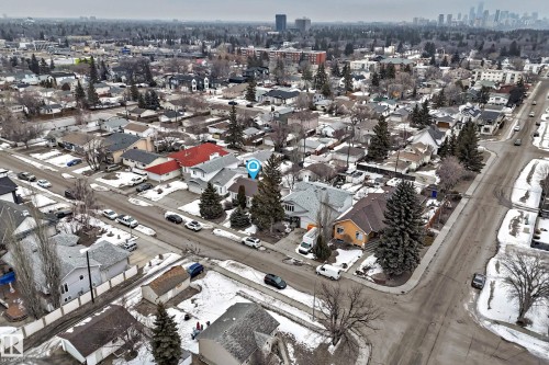 Aerial view of the neighborhood showcasing tree-lined streets, residential properties with varied roof colors, and a distant city skyline - 9813 152 Street, Edmonton, AB - Outdoor With View