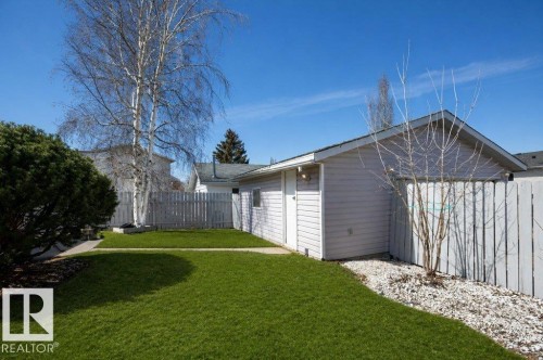 Manicured lawn area with a white picket fence, white gravel landscaping, mature birch trees, and an accessory building with horizontal siding - 10812 109 Street, Westlock, AB - Outdoor