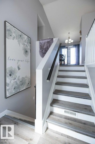 Split-level entryway featuring wood-finish flooring, a white staircase with wood-finish treads, and a contrasting black handrail - 10812 109 Street, Westlock, AB - Indoor Photo Showing Other Room