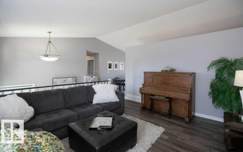 Expansive living area featuring vaulted ceilings, wood-finish flooring, and a modern pendant light fixture - 10812 109 Street, Westlock, AB - Indoor Photo Showing Living Room