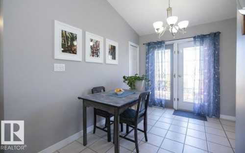 Dining space with a vaulted ceiling, tiled flooring, and double French doors with decorative glass - 10812 109 Street, Westlock, AB - Indoor Photo Showing Dining Room