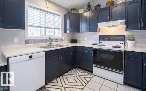 Kitchen featuring dark-toned cabinetry, light countertops, and a tile backsplash - 10812 109 Street, Westlock, AB - Indoor Photo Showing Kitchen With Double Sink