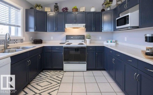 Kitchen featuring dark cabinetry, light countertops, and tile flooring - 10812 109 Street, Westlock, AB - Indoor Photo Showing Kitchen With Double Sink