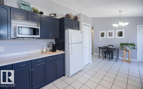 Kitchen featuring dark blue cabinetry, white countertops, built-in microwave, and tile flooring - 10812 109 Street, Westlock, AB - Indoor Photo Showing Kitchen