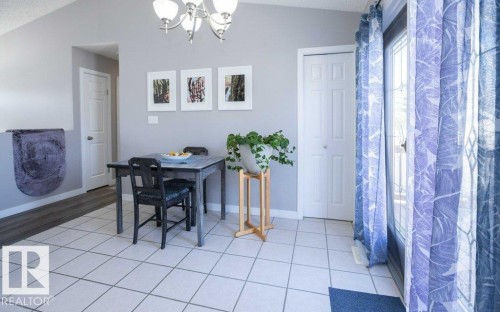 Spacious interior featuring a neutral color palette, ceramic tile flooring, and a chandelier light fixture - 10812 109 Street, Westlock, AB - Indoor
