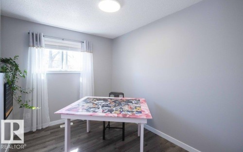 Bright room featuring a window with white window treatments, grey walls, and wood-finish flooring - 10812 109 Street, Westlock, AB - Indoor