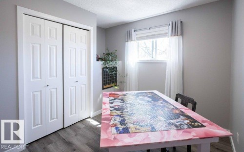 Room featuring a window, wood-finish flooring, and white bi-fold closet doors - 10812 109 Street, Westlock, AB - Indoor