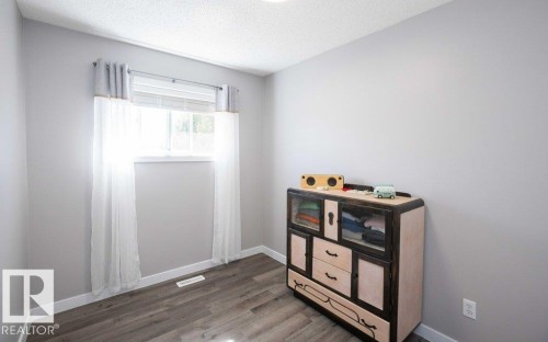 Window with white blinds and sheer curtains, light gray walls, and wood-finish flooring - 10812 109 Street, Westlock, AB - Indoor