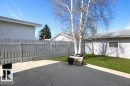 Concrete patio area with a white picket fence, green lawn, and mature trees - 10812 109 Street, Westlock, AB  - Outdoor 