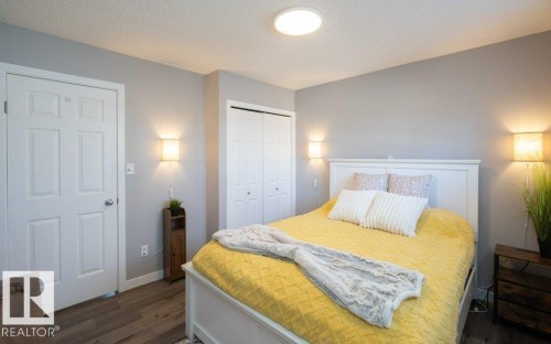 Bedroom featuring wood-finish flooring, a white paneled door, and two bifold closet doors - 10812 109 Street, Westlock, AB - Indoor Photo Showing Bedroom