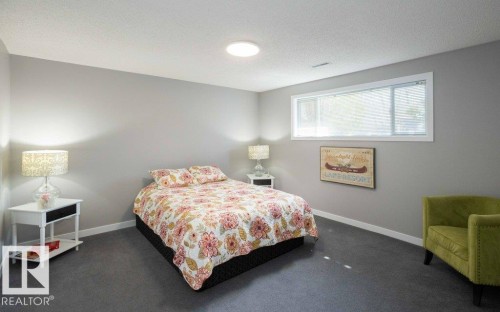 Spacious room featuring neutral gray walls, dark gray carpeting, a large window with white trim, and a contemporary flush-mount ceiling light - 10812 109 Street, Westlock, AB - Indoor Photo Showing Bedroom