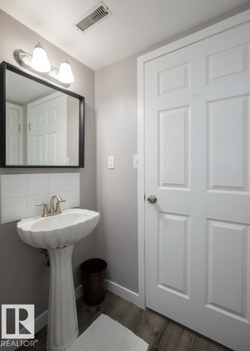 Pedestal sink with brushed nickel faucet, framed mirror, and tile backsplash - 10812 109 Street, Westlock, AB - Indoor Photo Showing Bathroom