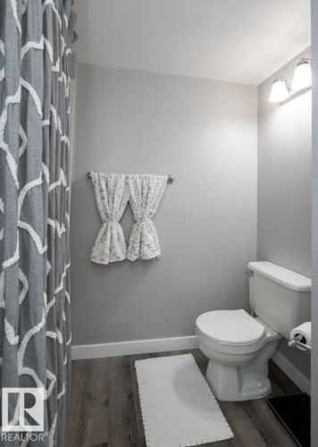 Bathroom featuring a white toilet, wood-finish flooring, and light gray wall paint - 10812 109 Street, Westlock, AB - Indoor Photo Showing Bathroom