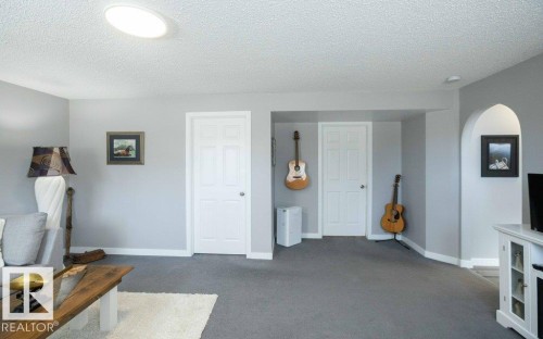 Spacious interior room featuring gray carpeting, light gray walls, and white baseboards - 10812 109 Street, Westlock, AB - Indoor