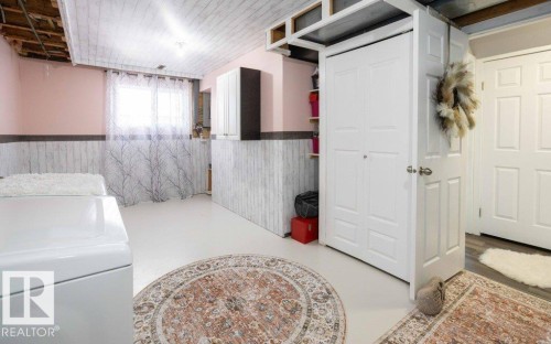 Finished lower level space featuring a drop ceiling with recessed lighting, white wood-finish wainscoting, and built-in shelving - 10812 109 Street, Westlock, AB - Indoor Photo Showing Laundry Room