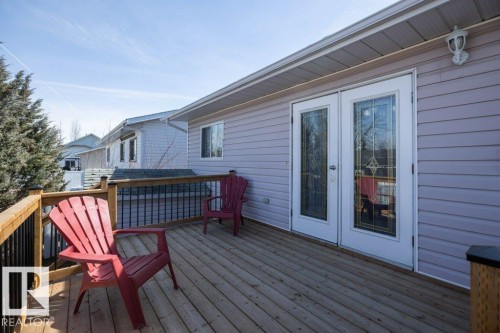Spacious outdoor deck with wood flooring and a wooden railing with black spindles - 10812 109 Street, Westlock, AB - Outdoor With Deck Patio Veranda With Exterior