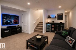 Carpeted recreation room featuring a built-in wet bar with a beverage cooler, media console, and recessed lighting - 
