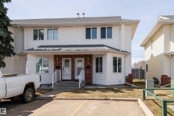 Duplex exterior featuring white siding and brick accents - 