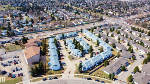 Residential development featuring multiple townhouse-style buildings with light-colored siding and grey roofing - #63 1033 Youville Dr W Nw, Edmonton, AB - Outdoor With View