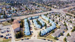 Residential development featuring multiple townhouse-style buildings with light-colored siding and grey roofing - 