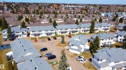 Residential development featuring multiple townhome-style units with light-colored exteriors and grey shingled roofs - 