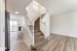 Staircase with carpeted treads and white wood balusters, complemented by light wood-finish flooring - 