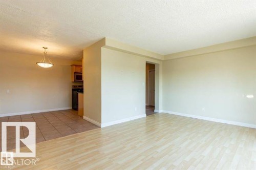 Open-concept living space featuring wood-finish flooring, a neutral color palette, and a semi-flush mount ceiling fixture - 307 8215 83 Avenue, Edmonton, AB - Indoor Photo Showing Other Room