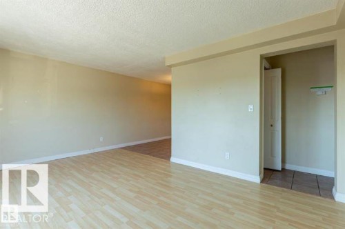 Open-concept living area featuring light wood-finish flooring and neutral painted walls - 307 8215 83 Avenue, Edmonton, AB - Indoor Photo Showing Other Room