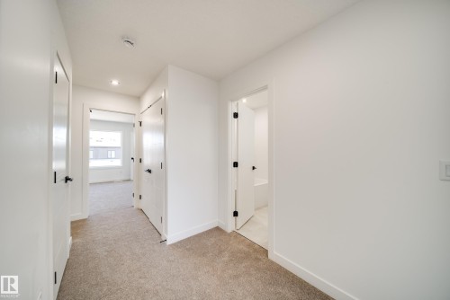 Interior hallway with neutral carpeting and white painted walls - 92 Blackbird Bend E, Fort Saskatchewan, AB - Indoor Photo Showing Other Room