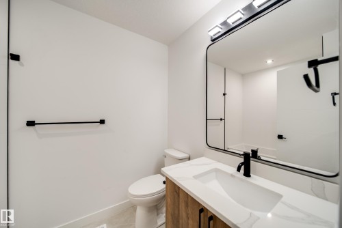 Bathroom featuring a modern vanity with wood-finish cabinetry, a white countertop, and an integrated rectangular sink - 92 Blackbird Bend E, Fort Saskatchewan, AB - Indoor Photo Showing Bathroom