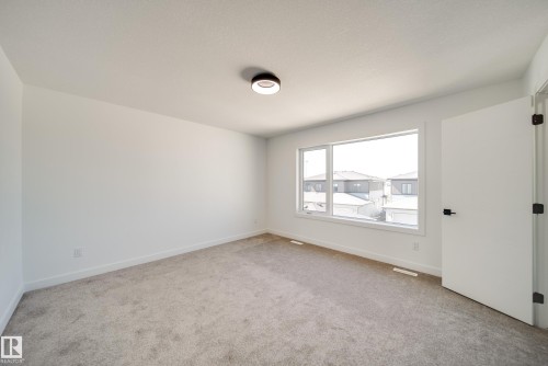 Carpeted interior room with white walls, a multi-pane window, and a white interior door with black hardware - 92 Blackbird Bend E, Fort Saskatchewan, AB - Indoor Photo Showing Other Room