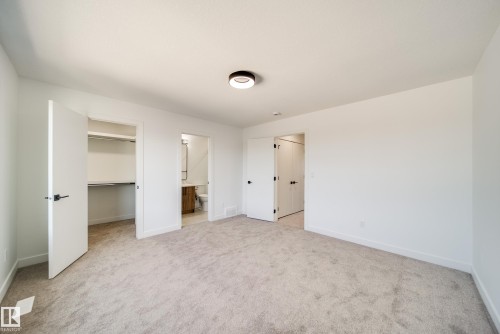 Spacious interior room with light grey carpet flooring and white walls - 92 Blackbird Bend E, Fort Saskatchewan, AB - Indoor Photo Showing Other Room