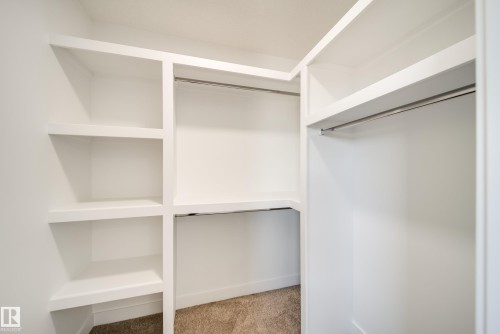 Custom white built-in shelving system with integrated hanging rods and carpet flooring - 92 Blackbird Bend E, Fort Saskatchewan, AB - Indoor With Storage