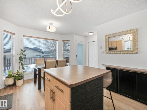 This inviting dining area features engineered hardwood flooring, bay windows with horizontal blinds, and a contemporary ceiling light fixture - 21360 88 Avenue, Edmonton, AB - Indoor