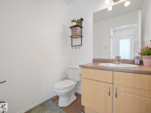 Bathroom featuring a vanity with light wood cabinetry, an integrated sink, and a large wall-mounted mirror - 21360 88 Avenue, Edmonton, AB - Indoor Photo Showing Bathroom