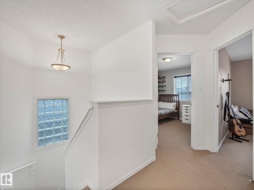 The property features a staircase with a glass block window, carpeted hallway, and an overhead light fixture - 21360 88 Avenue, Edmonton, AB - Indoor Photo Showing Other Room