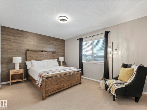 This bedroom features a striking wood-paneled accent wall, a light-colored carpet, and a window with blinds and curtains - 21360 88 Avenue, Edmonton, AB - Indoor Photo Showing Bedroom