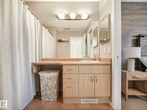 The bathroom features a light wood vanity with a built-in sink and ample storage, a large wall-mounted mirror, and overhead lighting - 21360 88 Avenue, Edmonton, AB - Indoor Photo Showing Bathroom