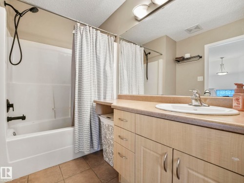 The bathroom features a bathtub with a shower, a vanity with a sink, and a large mirror - 21360 88 Avenue, Edmonton, AB - Indoor Photo Showing Bathroom