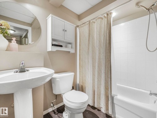 Bathroom featuring a pedestal sink with a chrome faucet, a white toilet, and a white shower-over-bath with white tiled walls - 21360 88 Avenue, Edmonton, AB - Indoor Photo Showing Bathroom