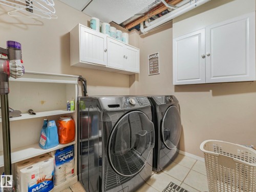 Laundry area featuring white cabinetry, a built-in shelving unit, and tile flooring - 21360 88 Avenue, Edmonton, AB - Indoor Photo Showing Laundry Room