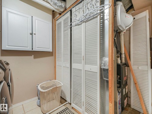 Laundry area featuring white cabinetry, louvered bi-fold doors, and a tiled floor - 21360 88 Avenue, Edmonton, AB - Indoor